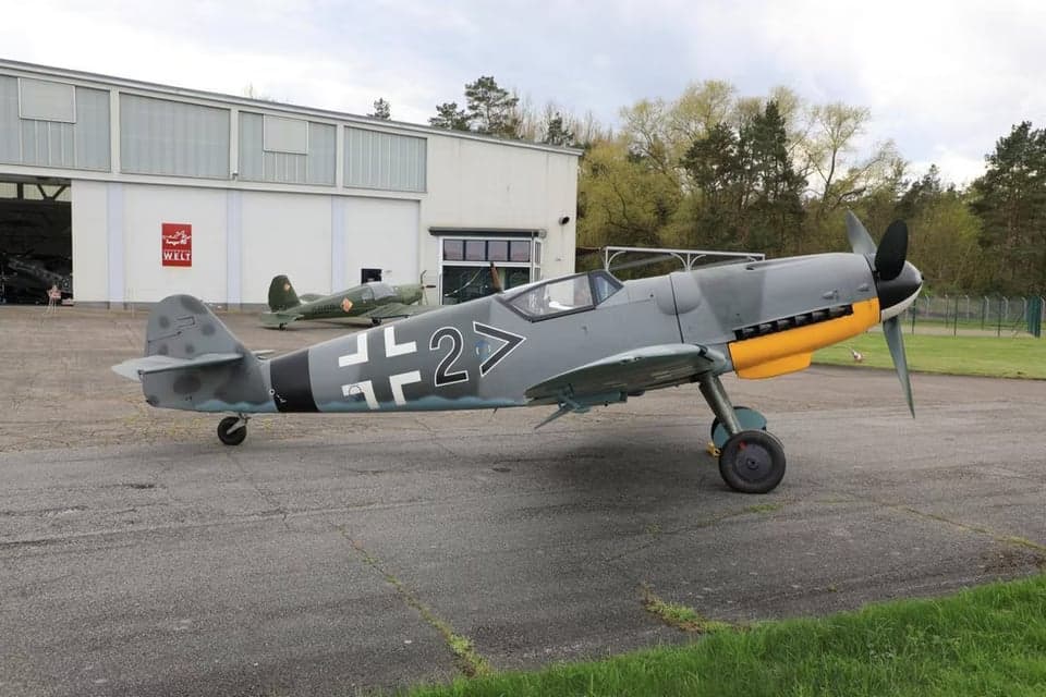 A Messerschmitt Bf 109 parked in front of a hangar.