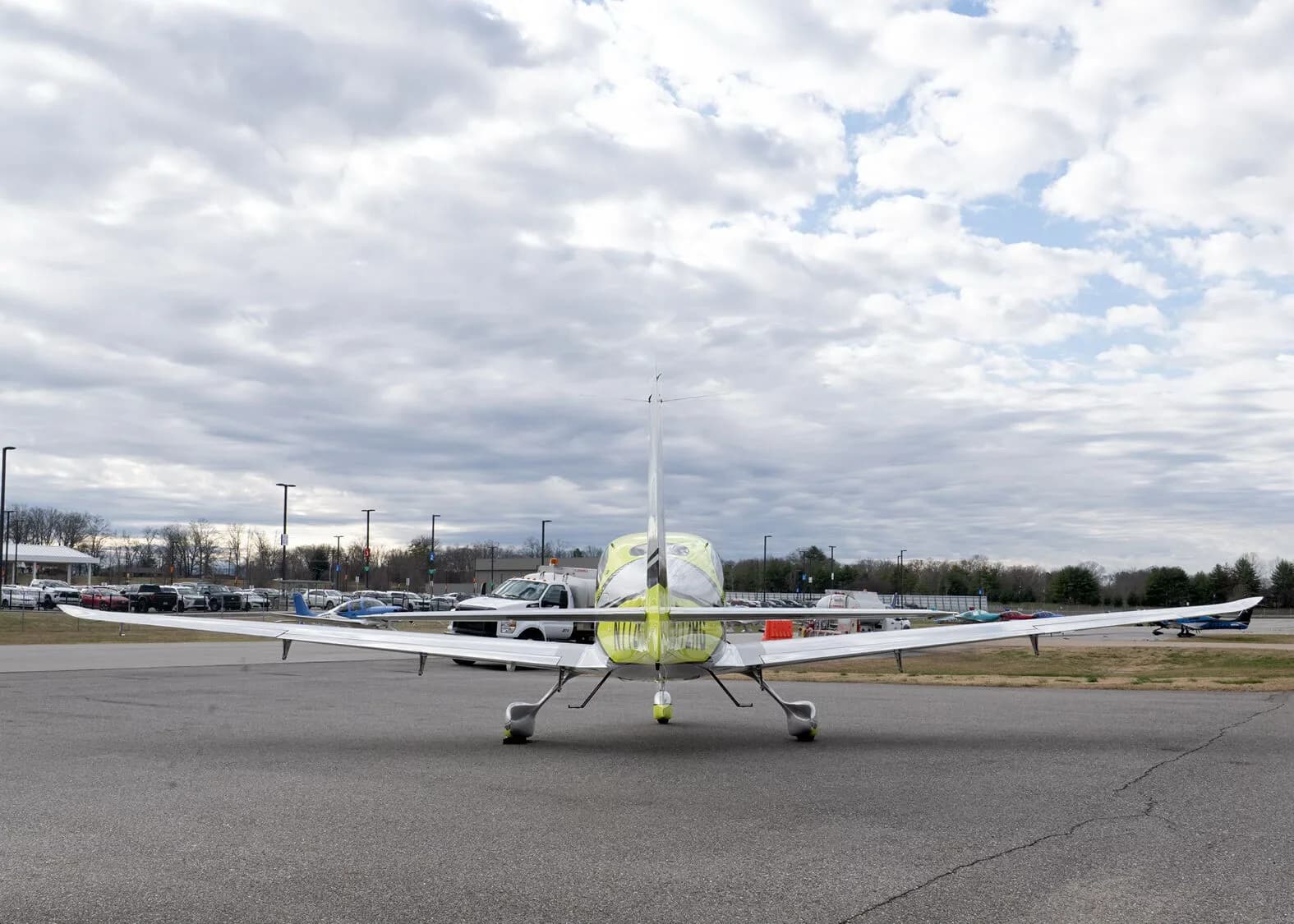 A direct rear view of the yellow and silver Cirrus SR22, N772RG, parked on an airfield.