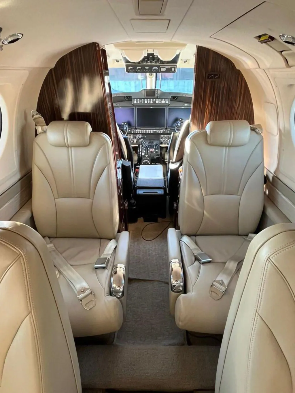 The aircraft's interior cabin with beige leather seats, looking forward towards the cockpit.