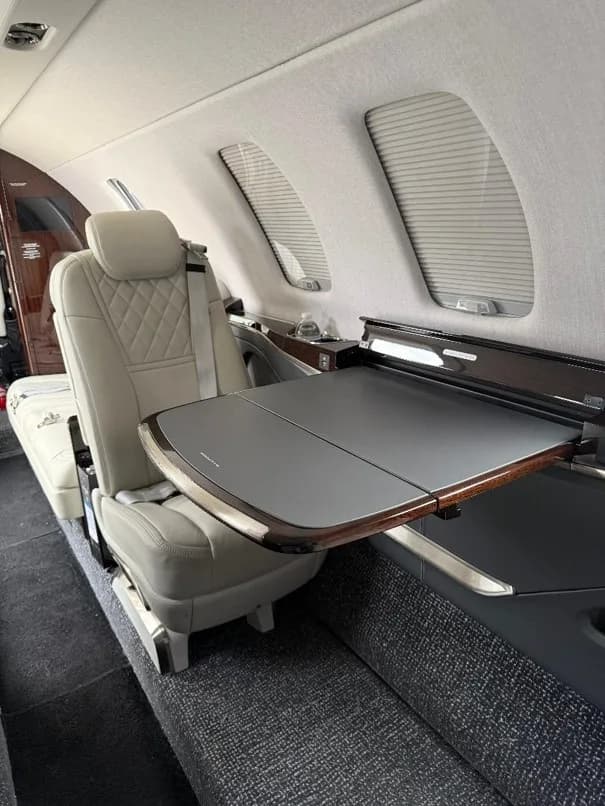 An interior view showing a light-colored quilted leather seat and a deployed fold-out table.