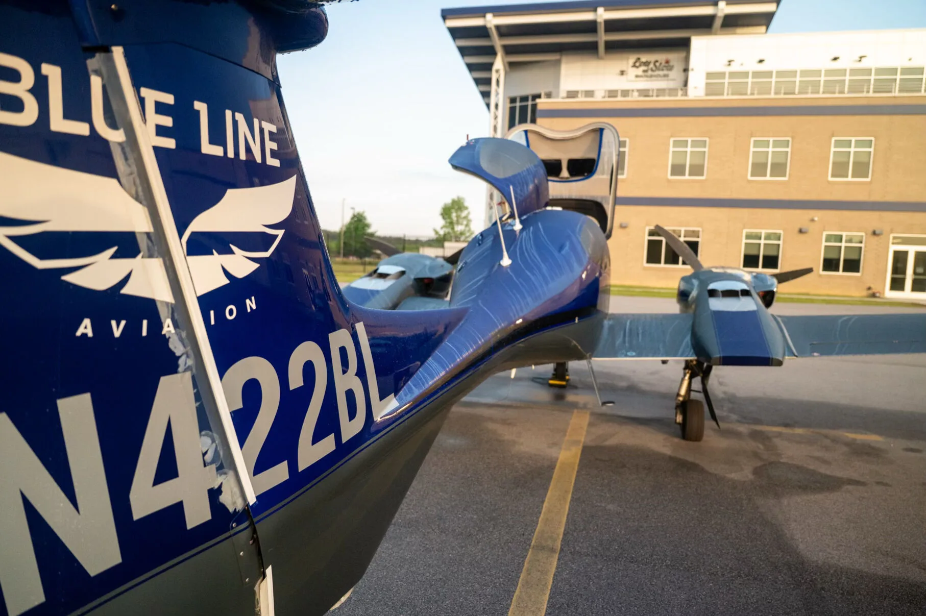 Close-up view of the blue tail of the Diamond DA42NG aircraft, N422BL, with a building in the background.