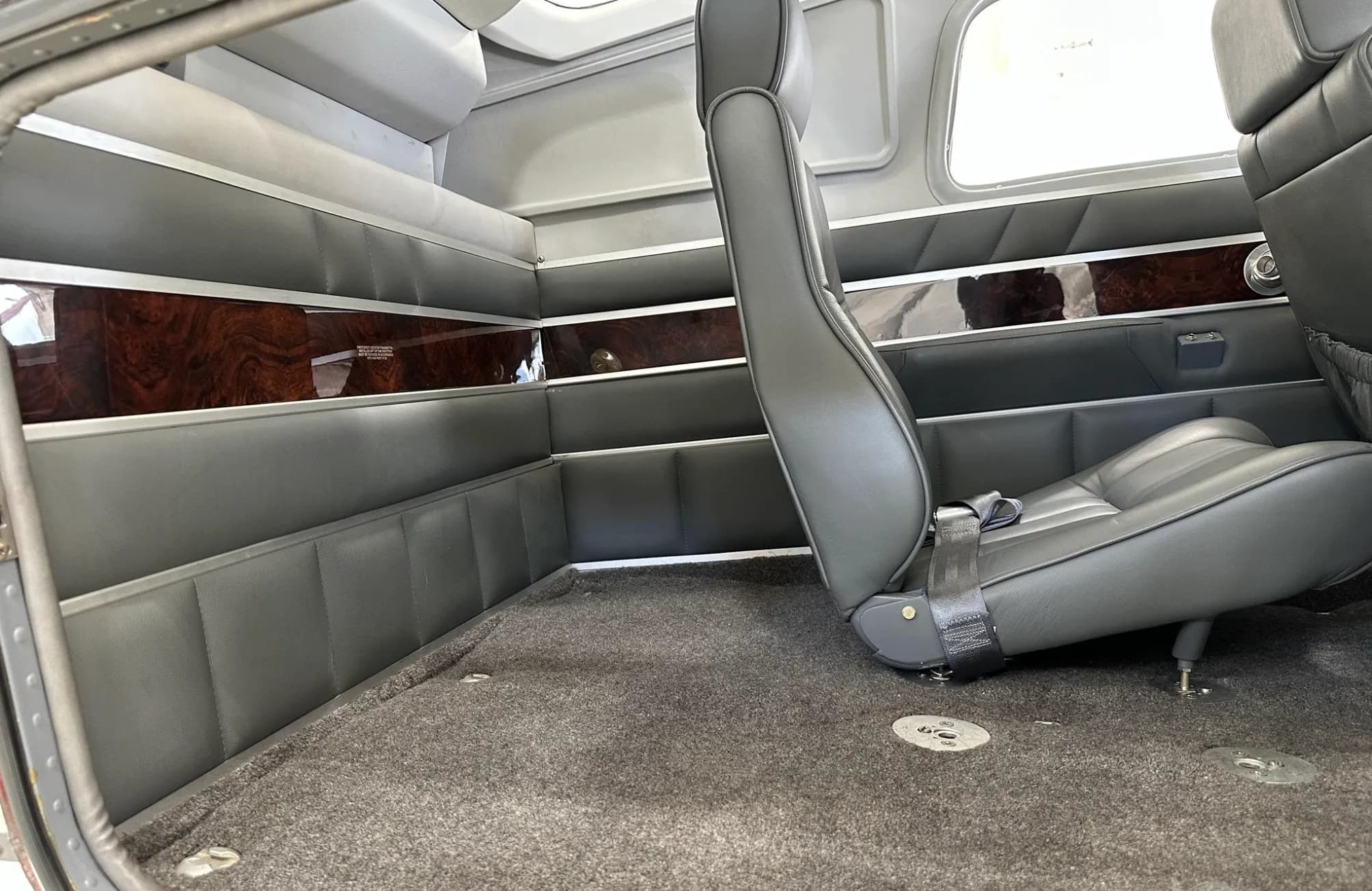 The aircraft's cabin interior features gray seats and wood-grain paneling along the walls.