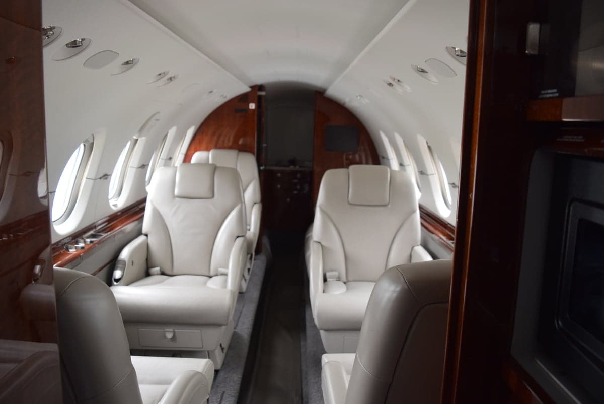 View of the aircraft cabin with cream-colored leather seats and wood trim.