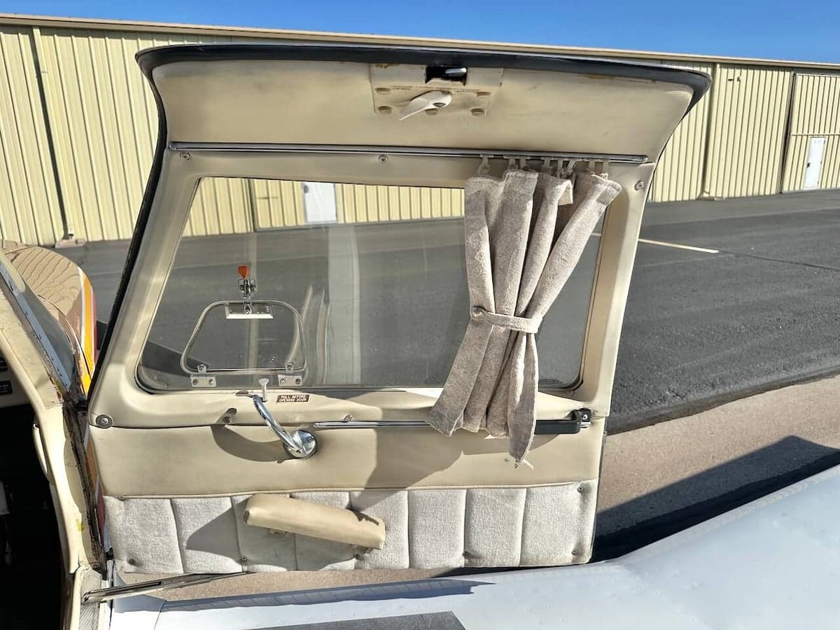 Open aircraft door showing the interior paneling and window with curtain.