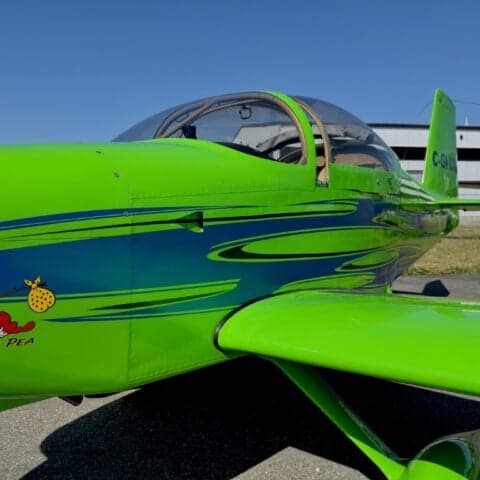 Close-up of the side of a green aircraft with blue accents and a cartoon character.