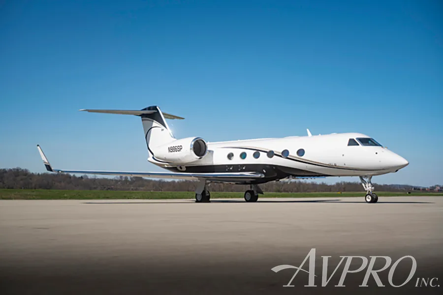 A white and black Gulfstream G550 (N986SP) parked on a tarmac under a clear blue sky.