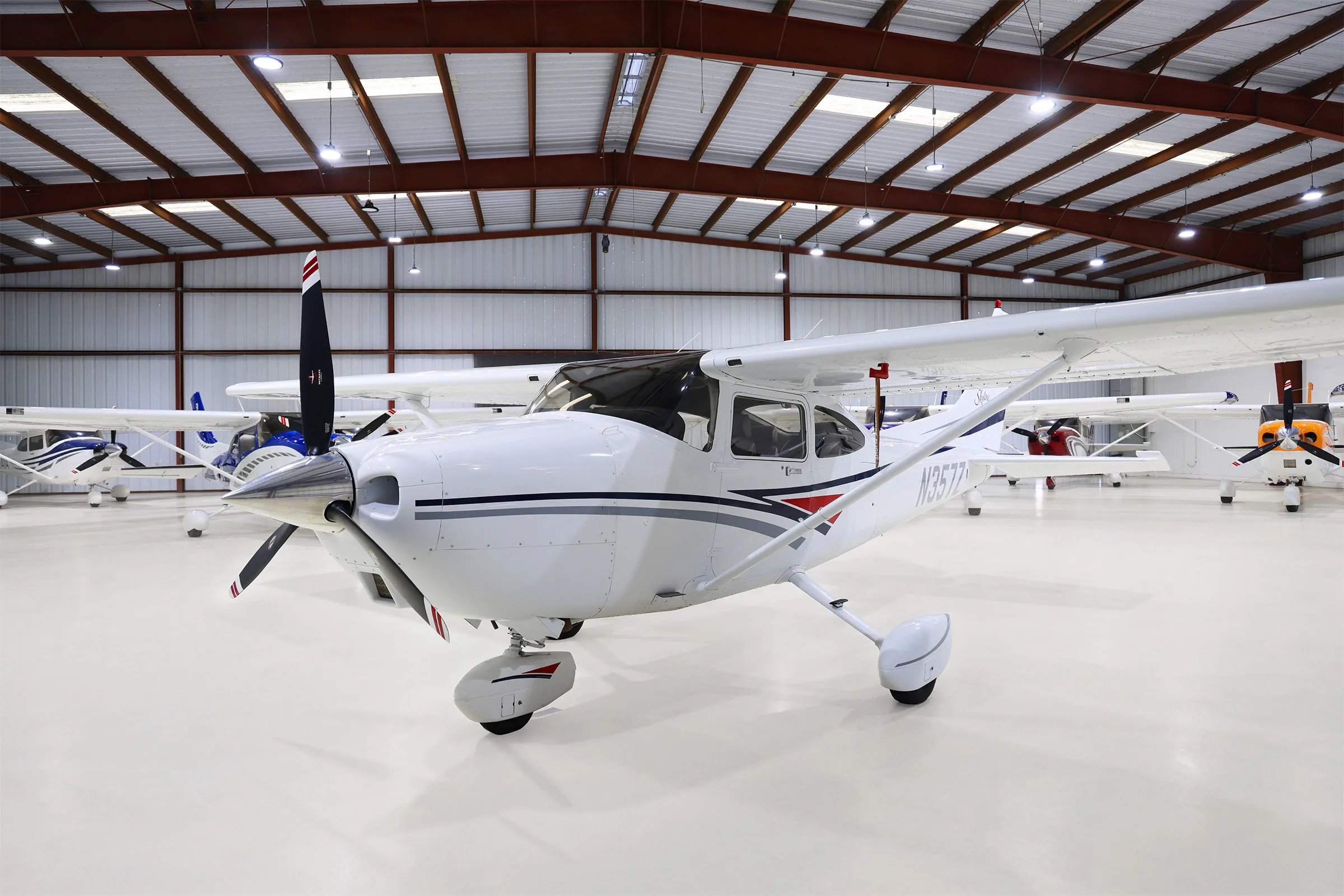 Front-left view of a white Cessna Skylane N357Z with grey and red stripes, parked in a hangar.