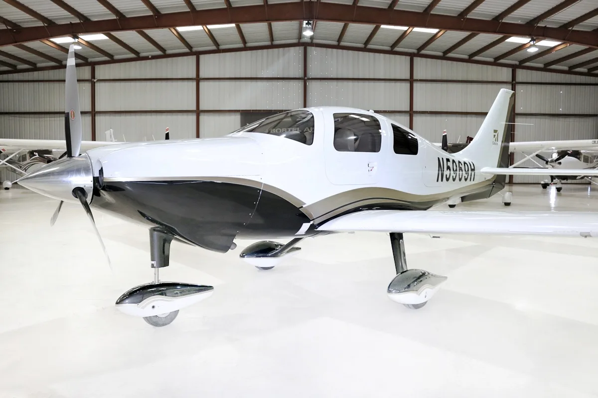 A white and black single-engine aircraft, N5969H, with a propeller, parked in a hangar.