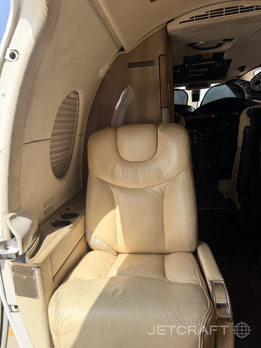 A close-up of a tan leather passenger seat inside a private jet cabin.