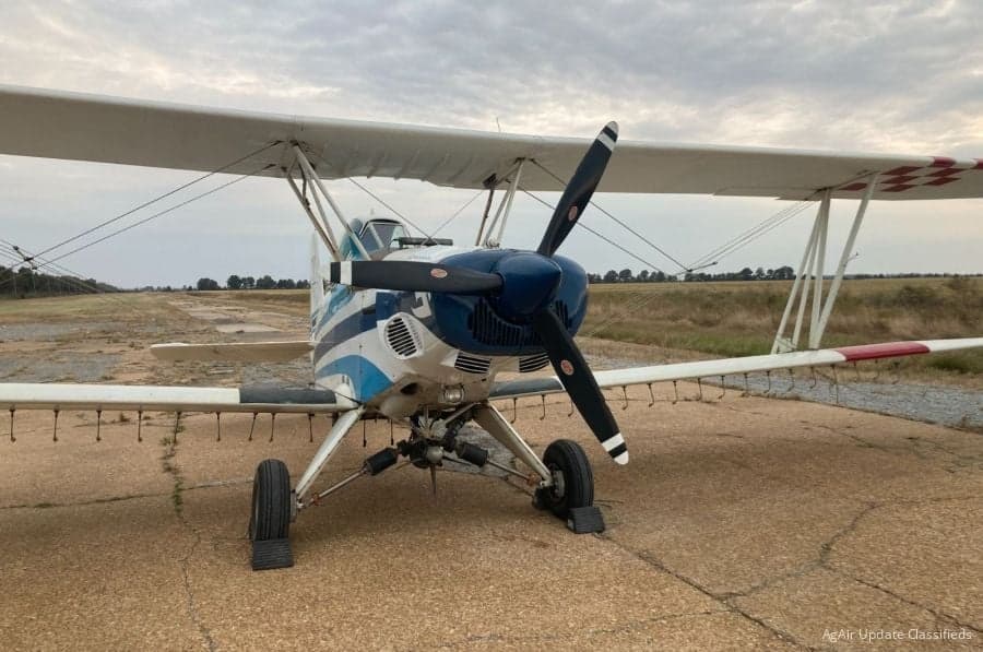 Front view of a blue and white biplane crop duster on a runway.