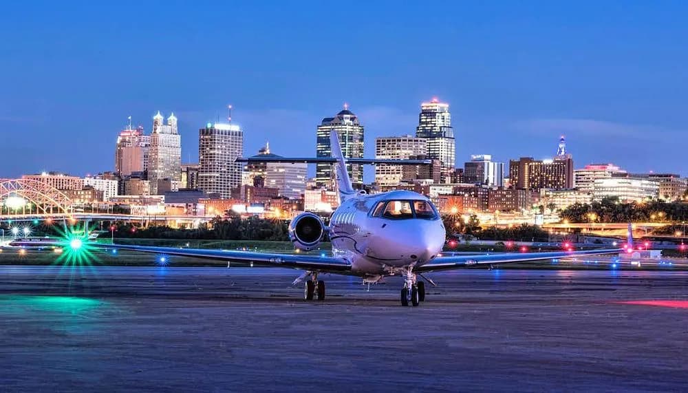 A white Hawker 800XP business jet, N900BF, viewed from the front on a runway at night with a city skyline.