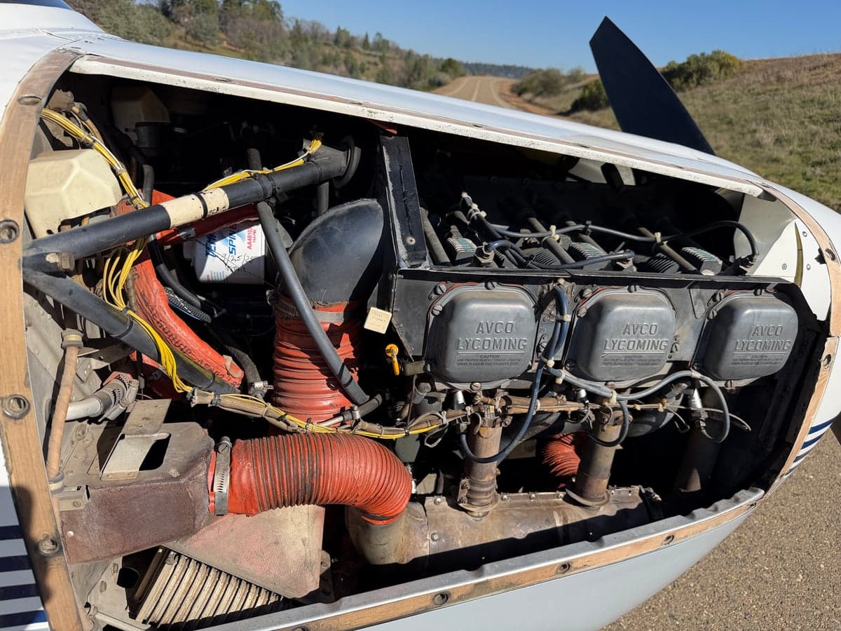 The aircraft's engine compartment is open, revealing the Lycoming engine.