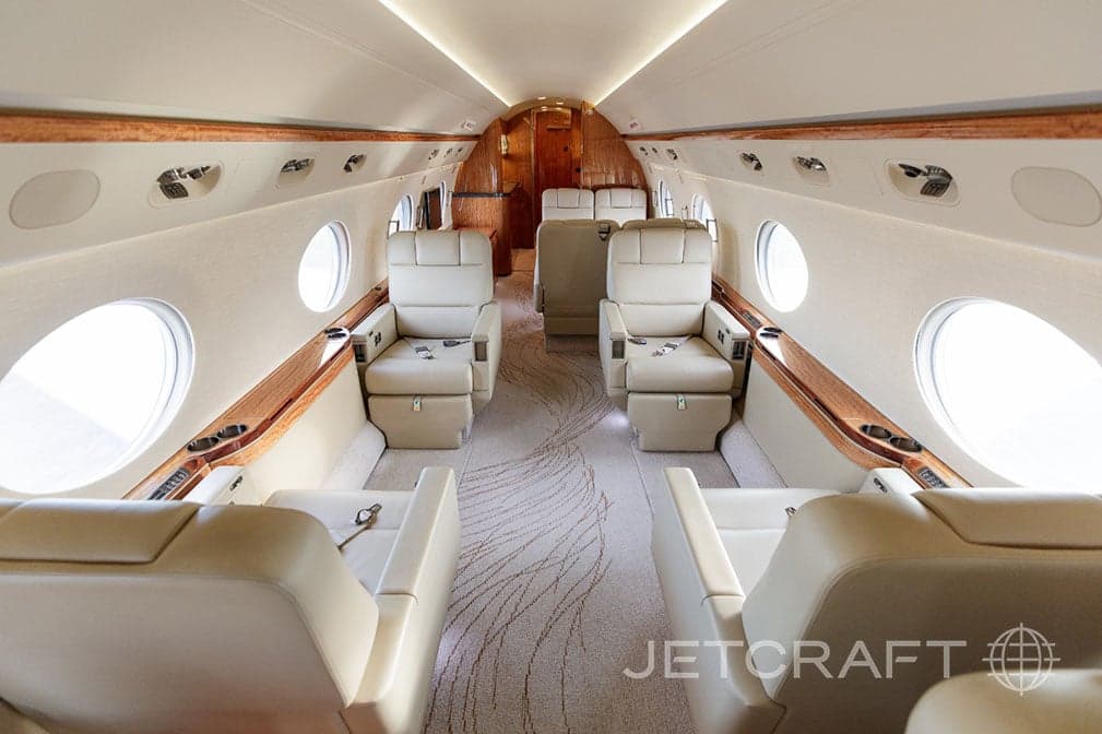 View of the interior of a jet with leather seats and carpet.