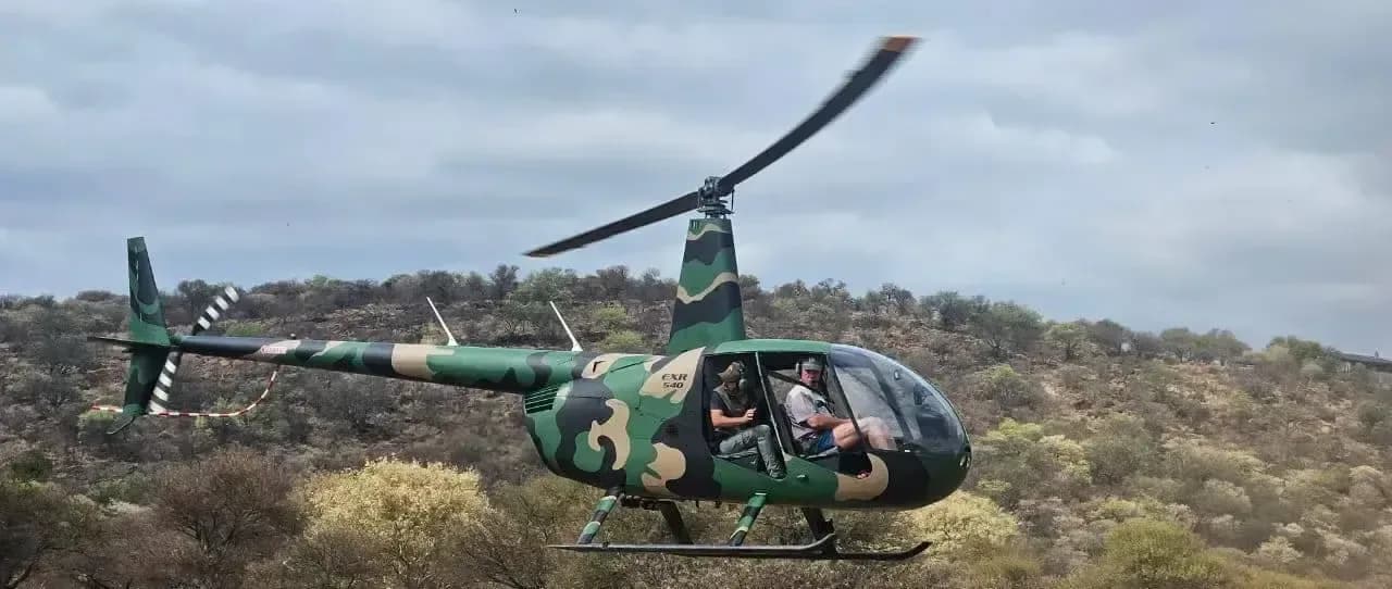 Robinson R-40 helicopter in flight with a camouflage paint scheme.