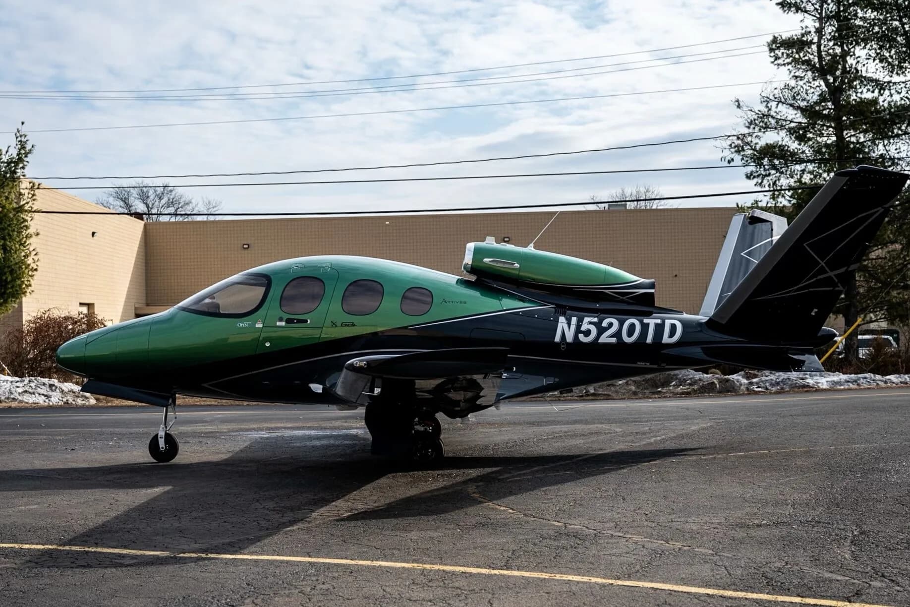 A side view of the Cirrus Vision Jet N520TD in green and black paint scheme on an airfield.