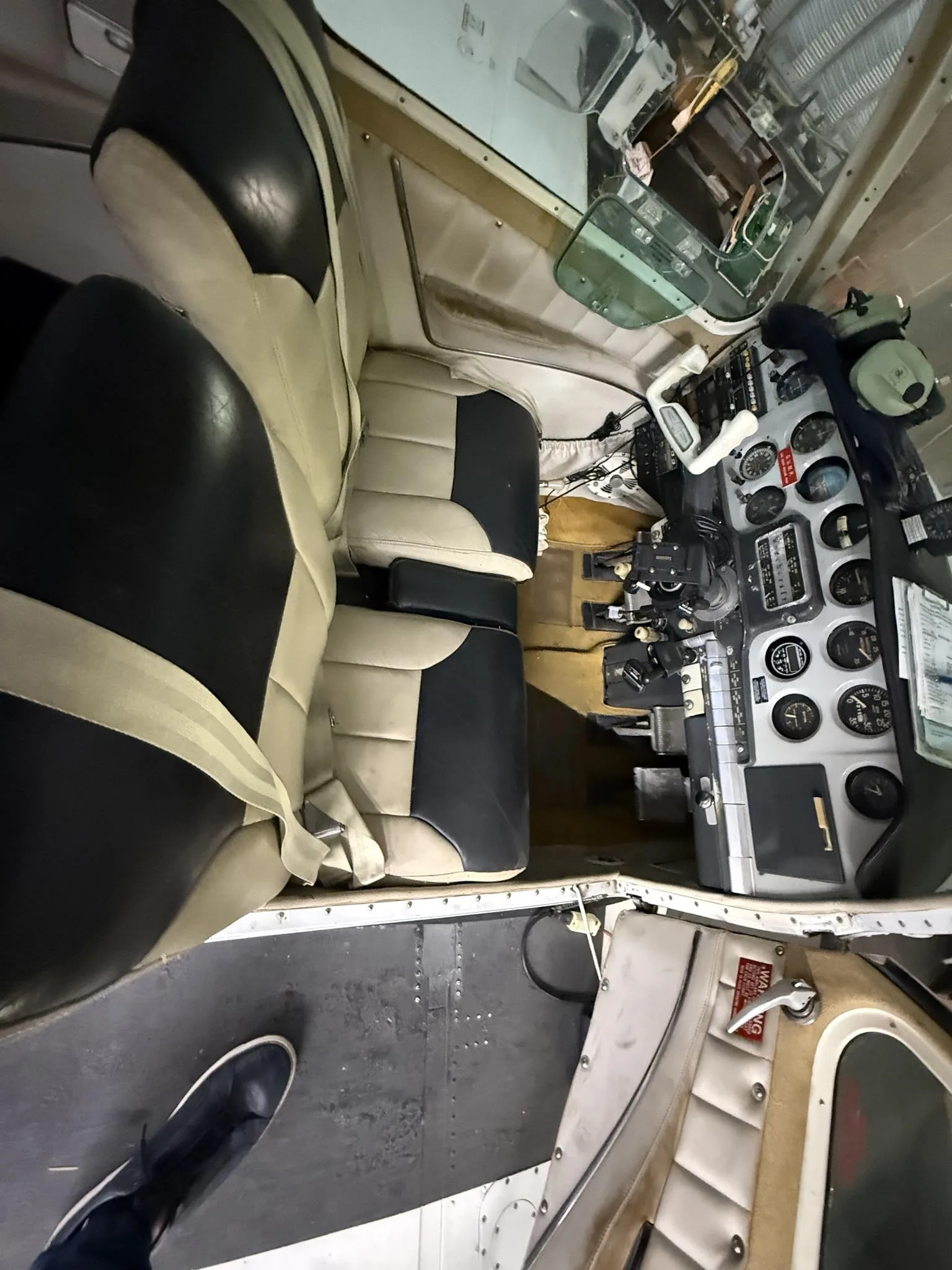 An overhead view of the aircraft's two-tone black and tan interior seats and the cockpit instruments.