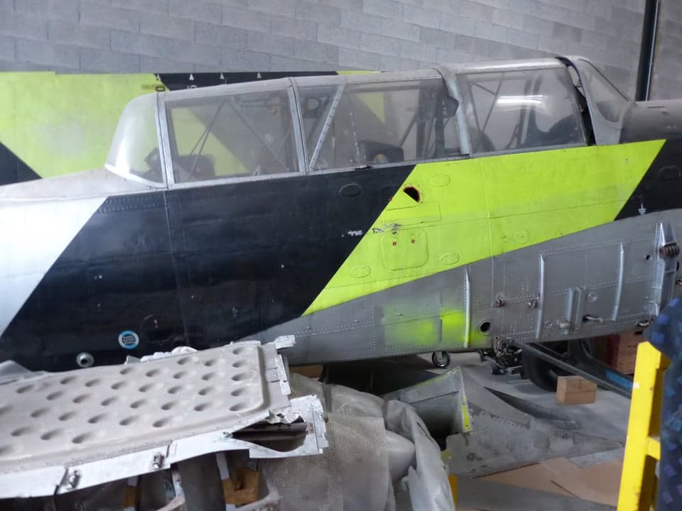 Aircraft fuselage and parts in a hangar.