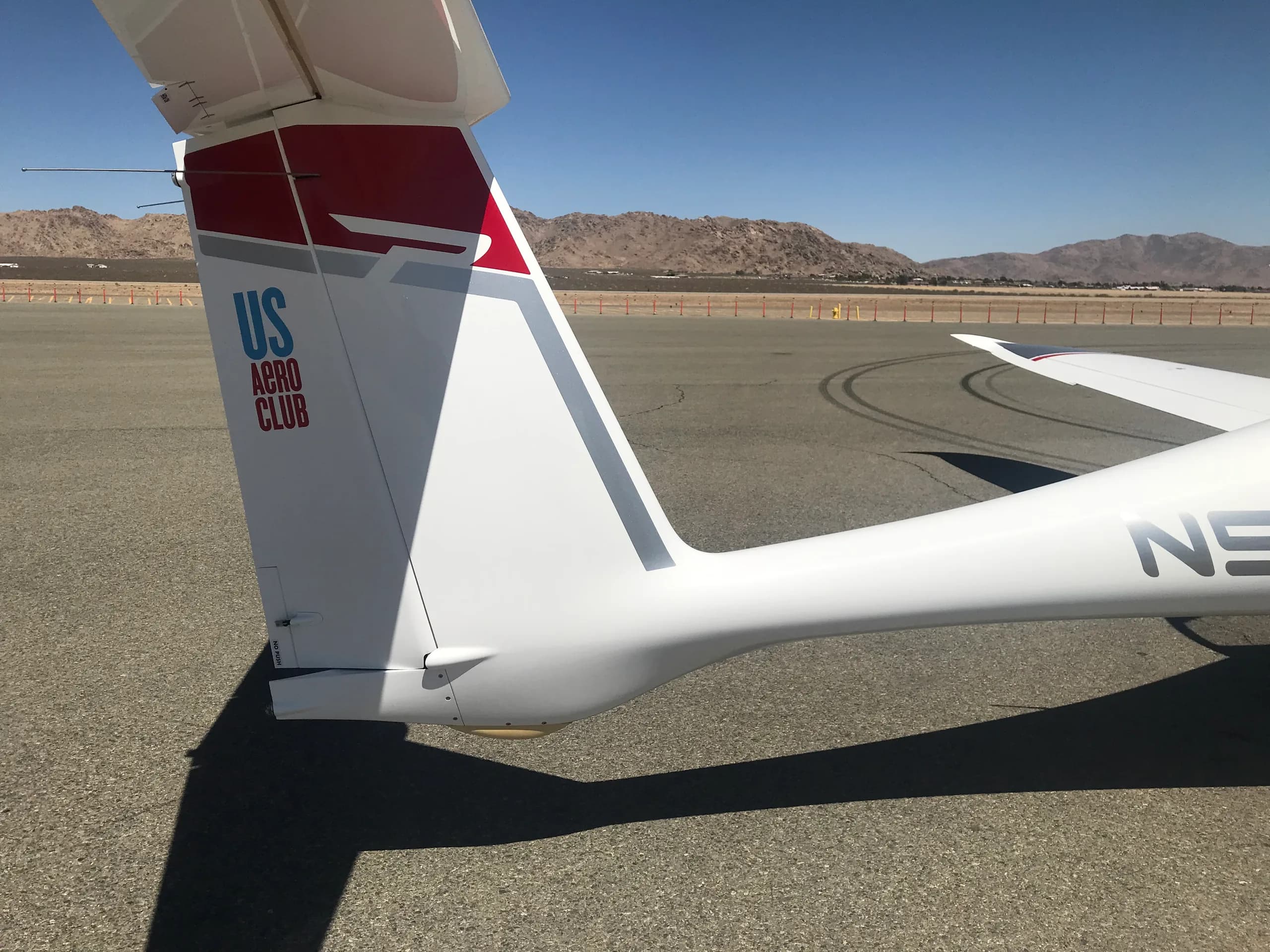 A close-up of the white tail of a Pipistrel Panthera aircraft with red and gray accents, showing "US AERO CLUB" text.