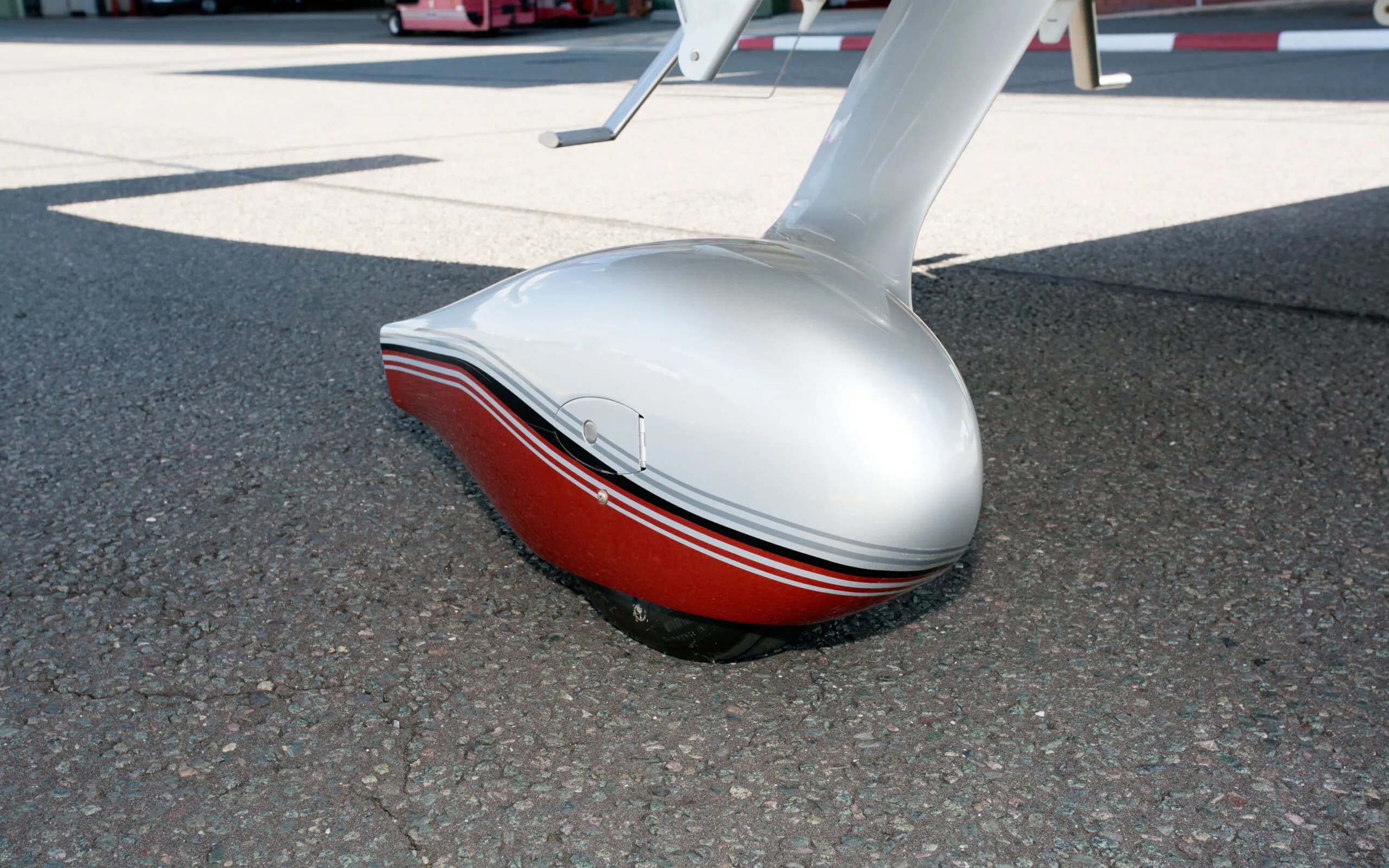 A close-up of the red and silver main landing gear fairing of a Cirrus SR22T GTS aircraft on an asphalt surface.