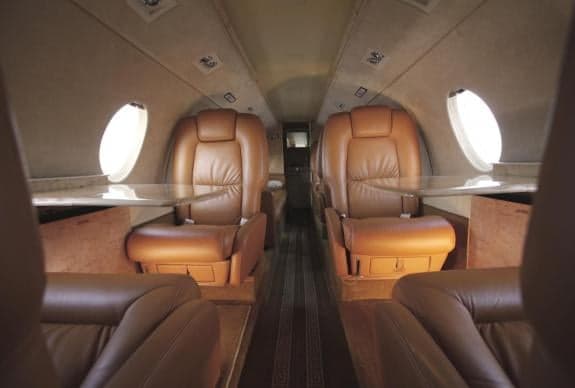 Interior view of the aircraft cabin with leather seats and tables.