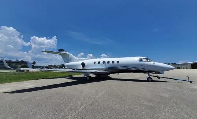 A white Cessna Citation X business jet parked on an asphalt tarmac under a blue sky with clouds.