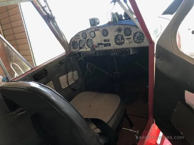The cockpit of a light aircraft showing the instrument panel with various gauges and a single seat.
