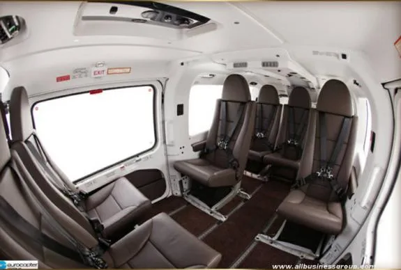 Interior view of the helicopter cabin with brown leather seats and seatbelts.