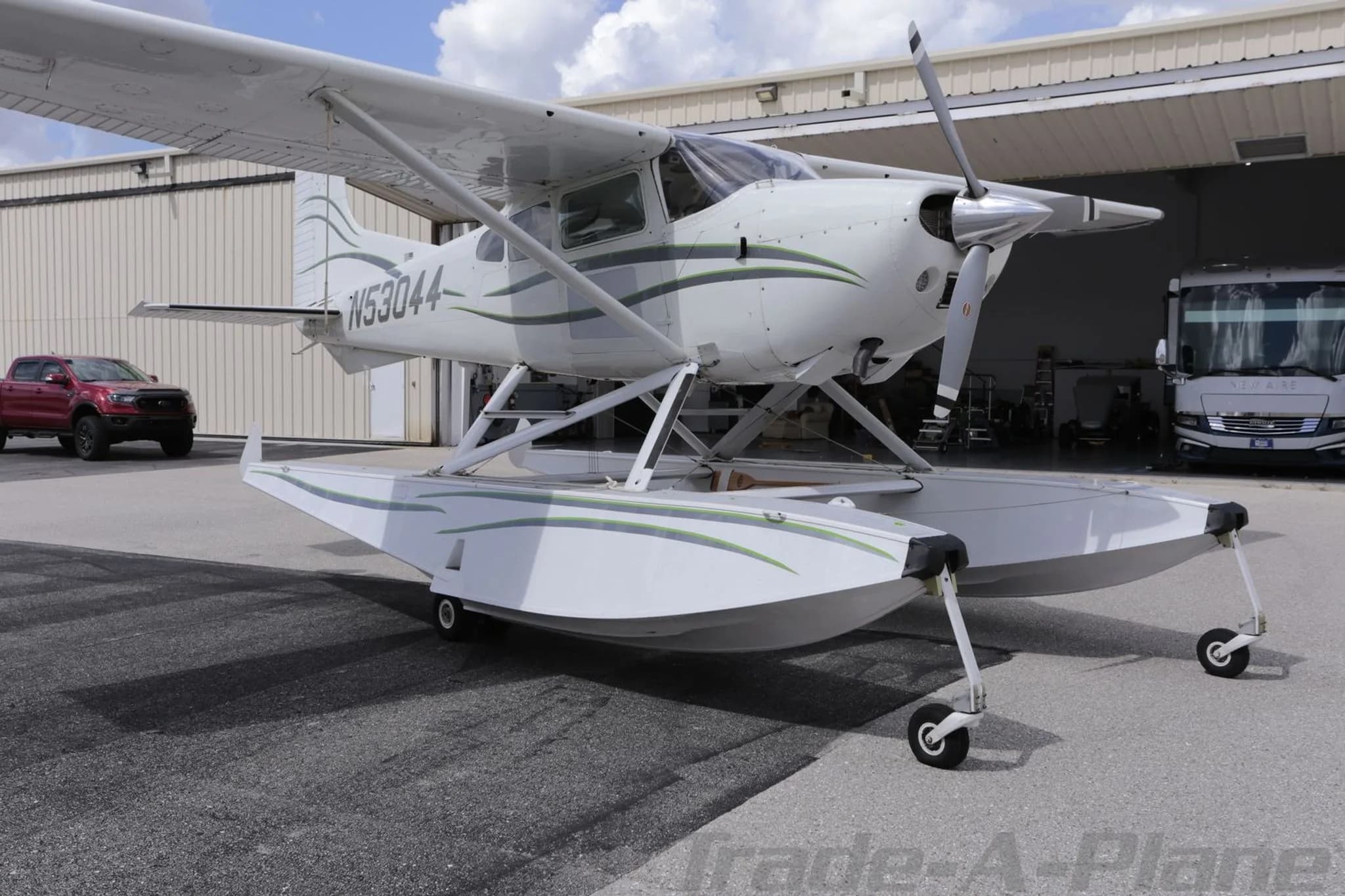 A front-quarter view of the Cessna 180 Skywagon seaplane (N53044), highlighting its floats and propeller.