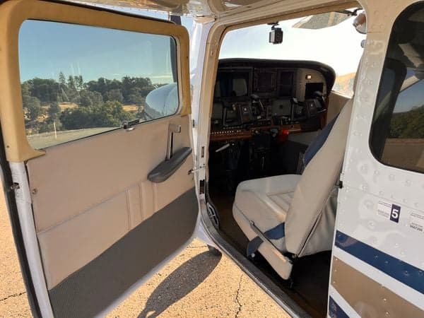 View of the cockpit and front seats of N738JZ through the open door.