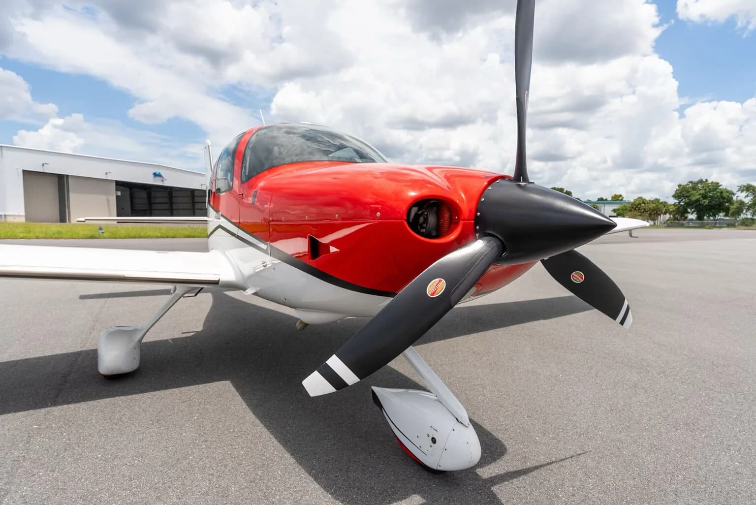 A low-angle front-side view of the red and white Cirrus SR22 aircraft on an airfield.