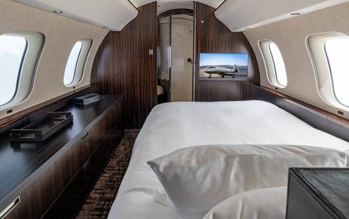 Aircraft interior with a couch, table, and a monitor displaying an aircraft image.