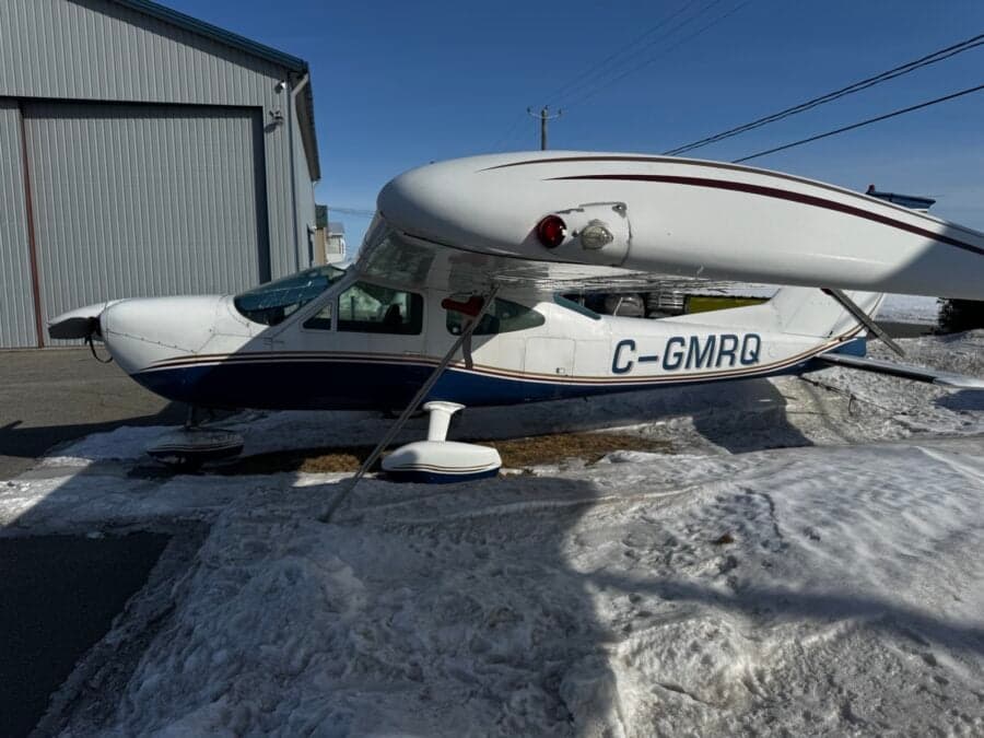 A Cessna aircraft with registration C-GMRQ parked near a hangar in winter.