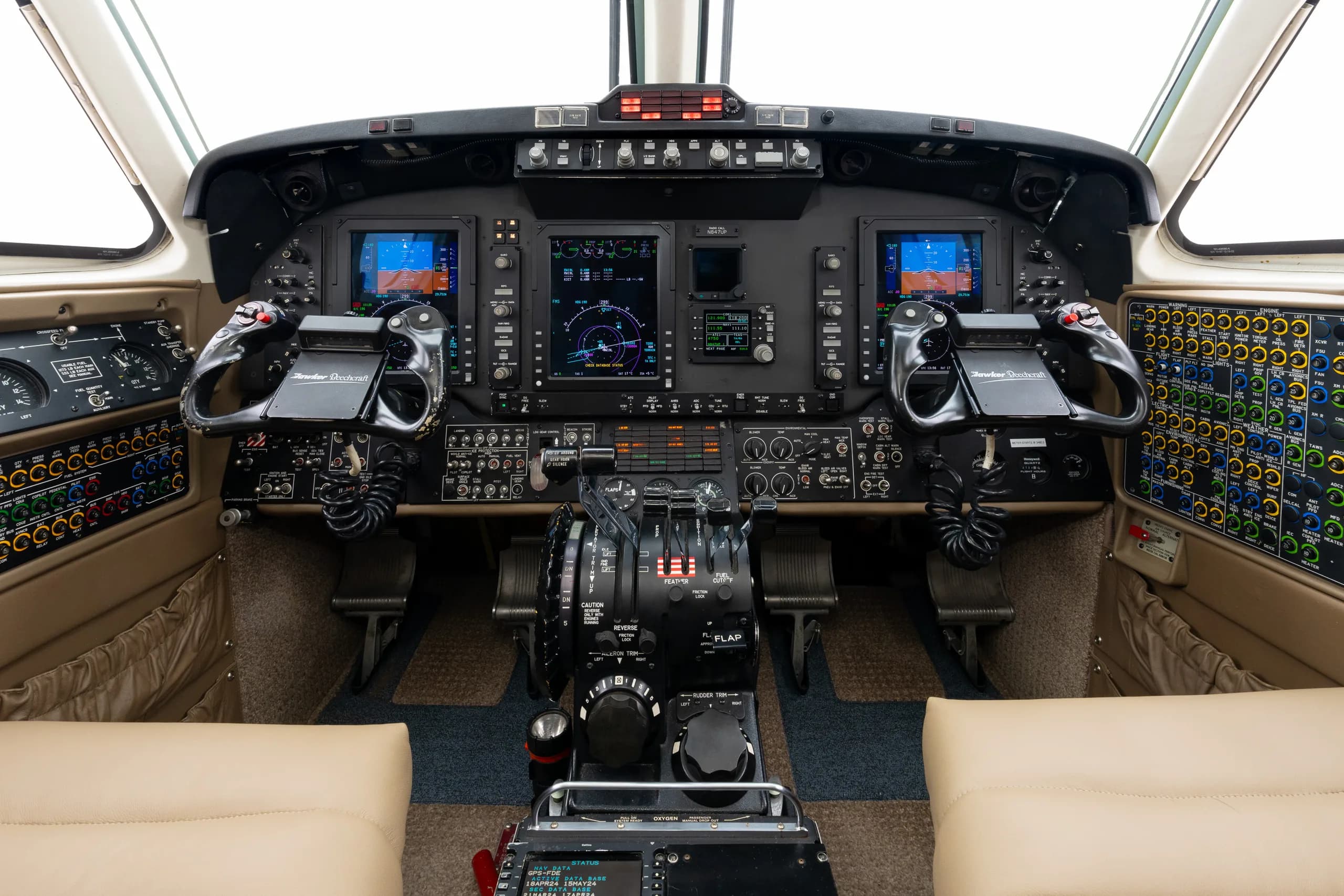 The cockpit of a twin-turboprop aircraft, featuring a modern glass cockpit display and numerous switches and controls.