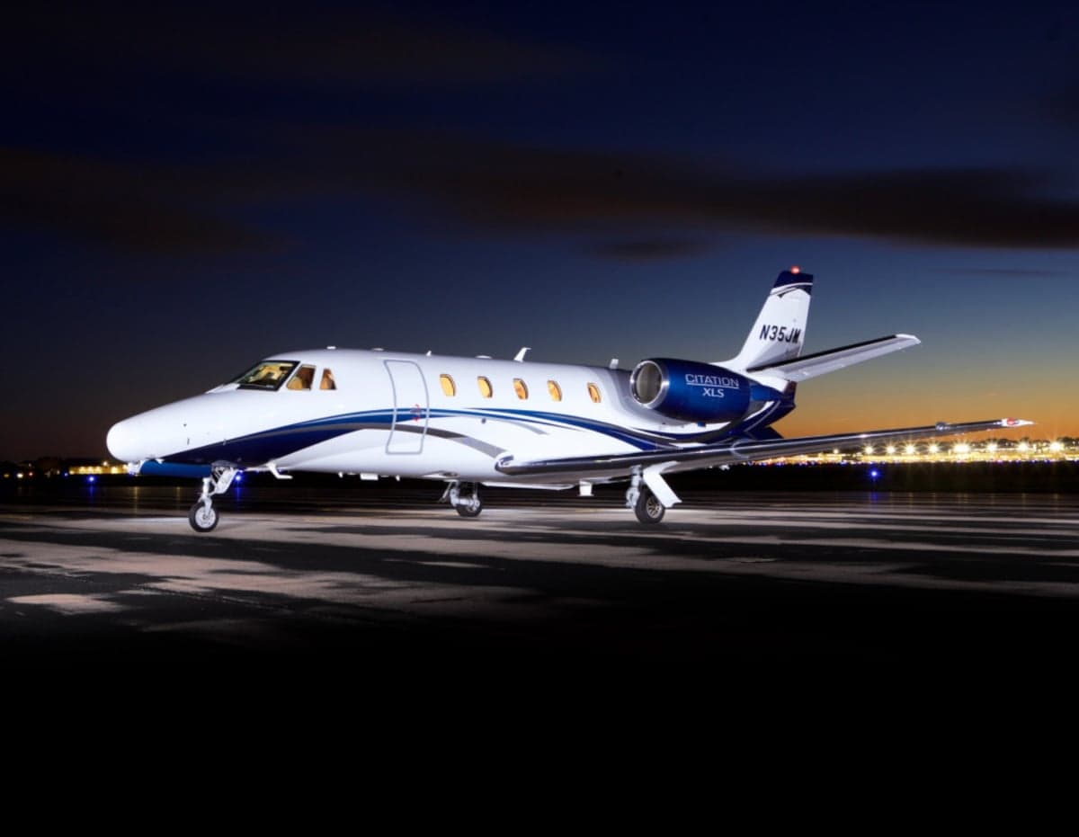 A Citation XLS aircraft on the tarmac at night.