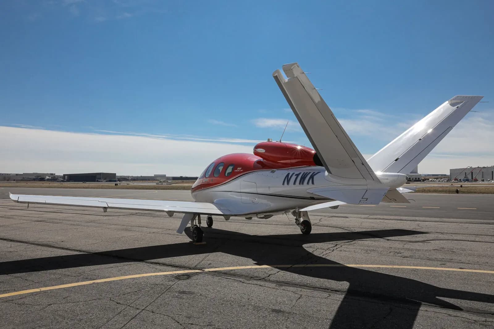 A red and white Cirrus Vision Jet (N1WK) parked on a tarmac, viewed from the rear-right.