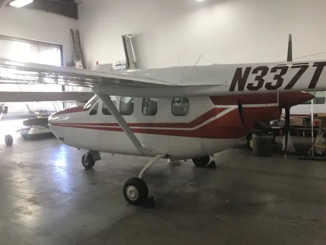A side view of a white and red Cessna 337 Skymaster aircraft with registration N337T in a hangar.