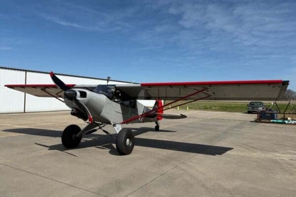 A gray and red N413SM aircraft is parked on the tarmac on a sunny day.