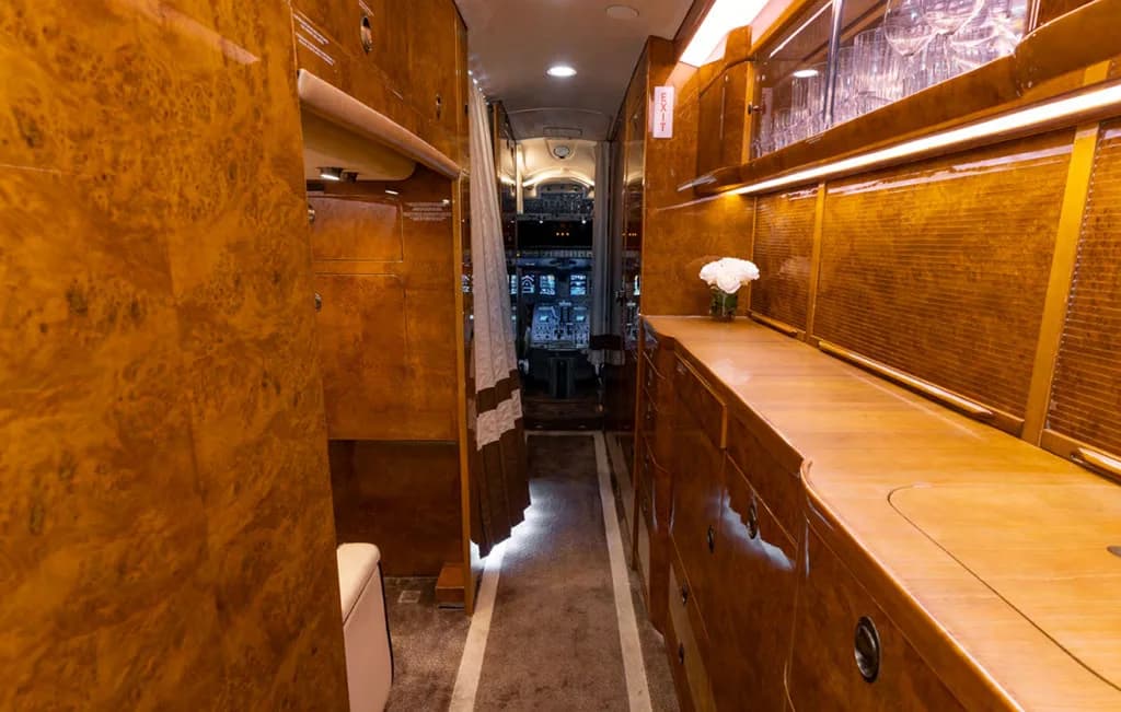 A view down the aircraft's galley with rich wood paneling, leading towards the cockpit visible in the distance.