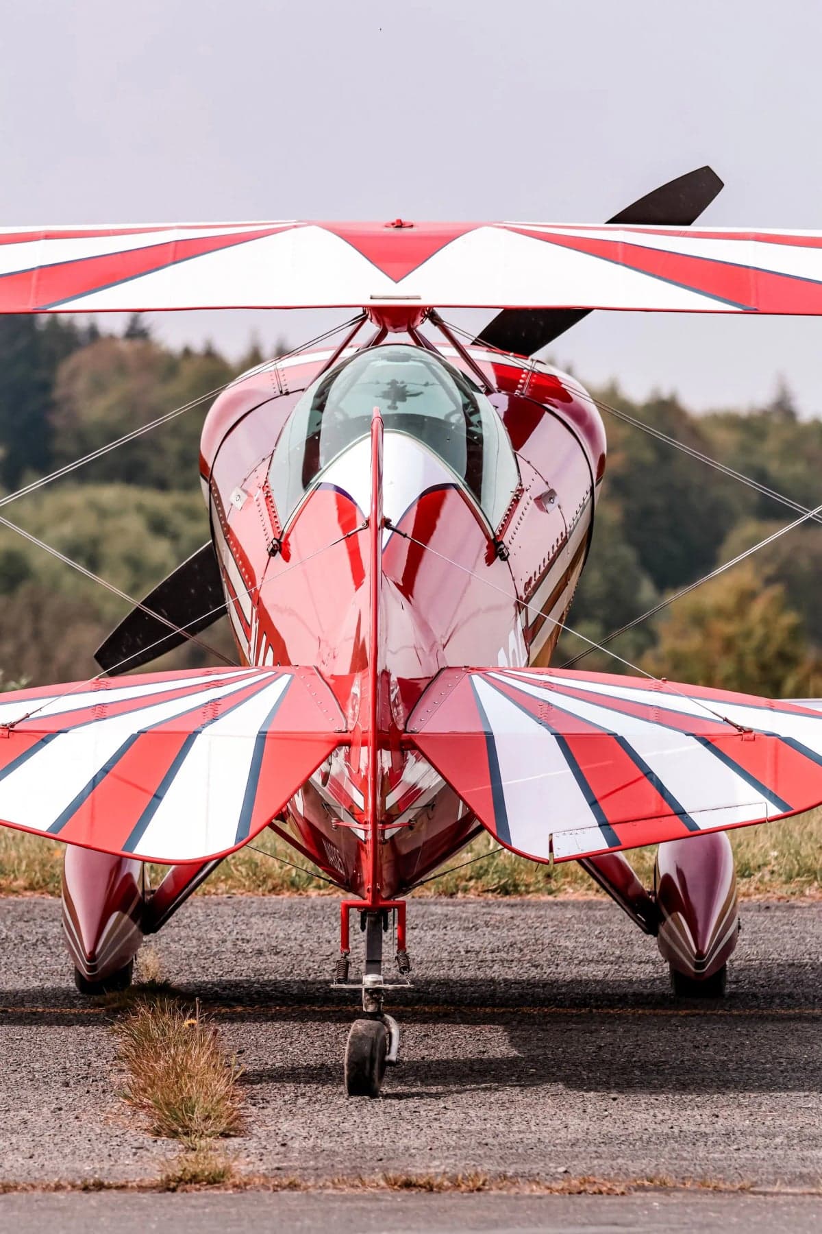 A red and white Pitts S-1T biplane with registration N49325 parked on the grass.