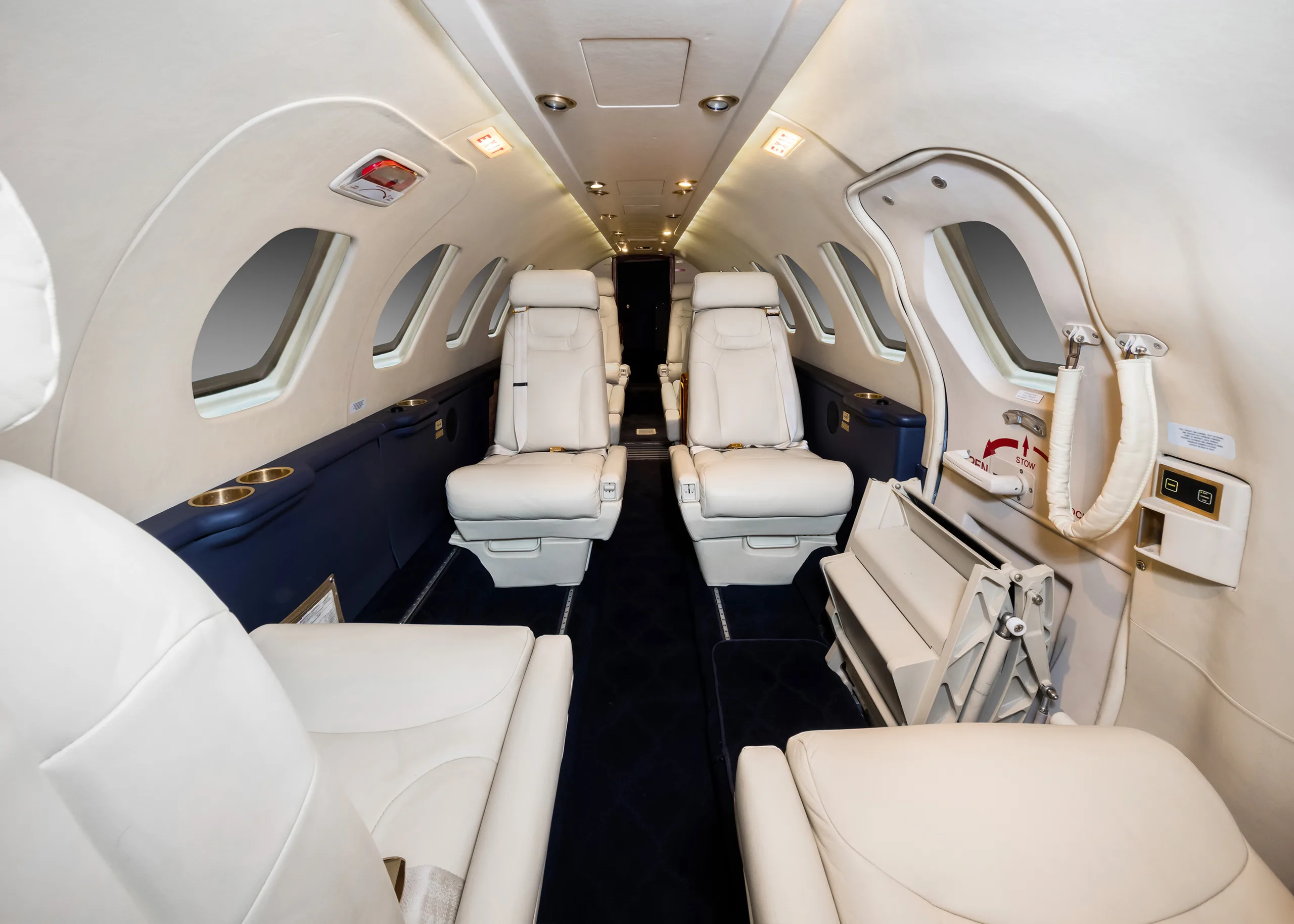 Interior view of the aircraft cabin with white leather seats and blue accents.