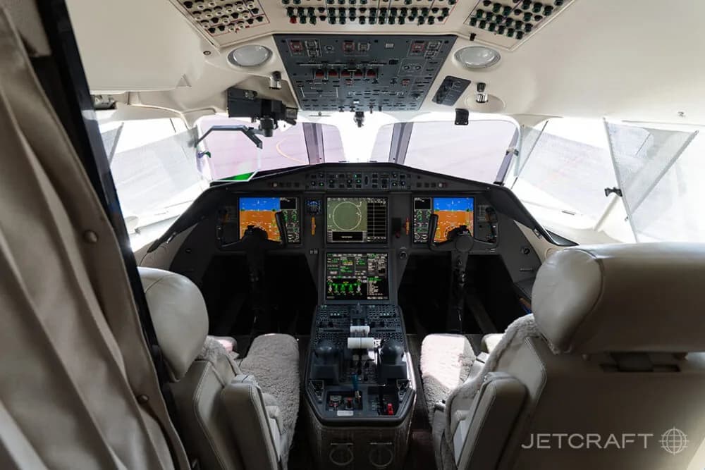 The modern cockpit of a business jet with multiple digital displays and two pilot seats.