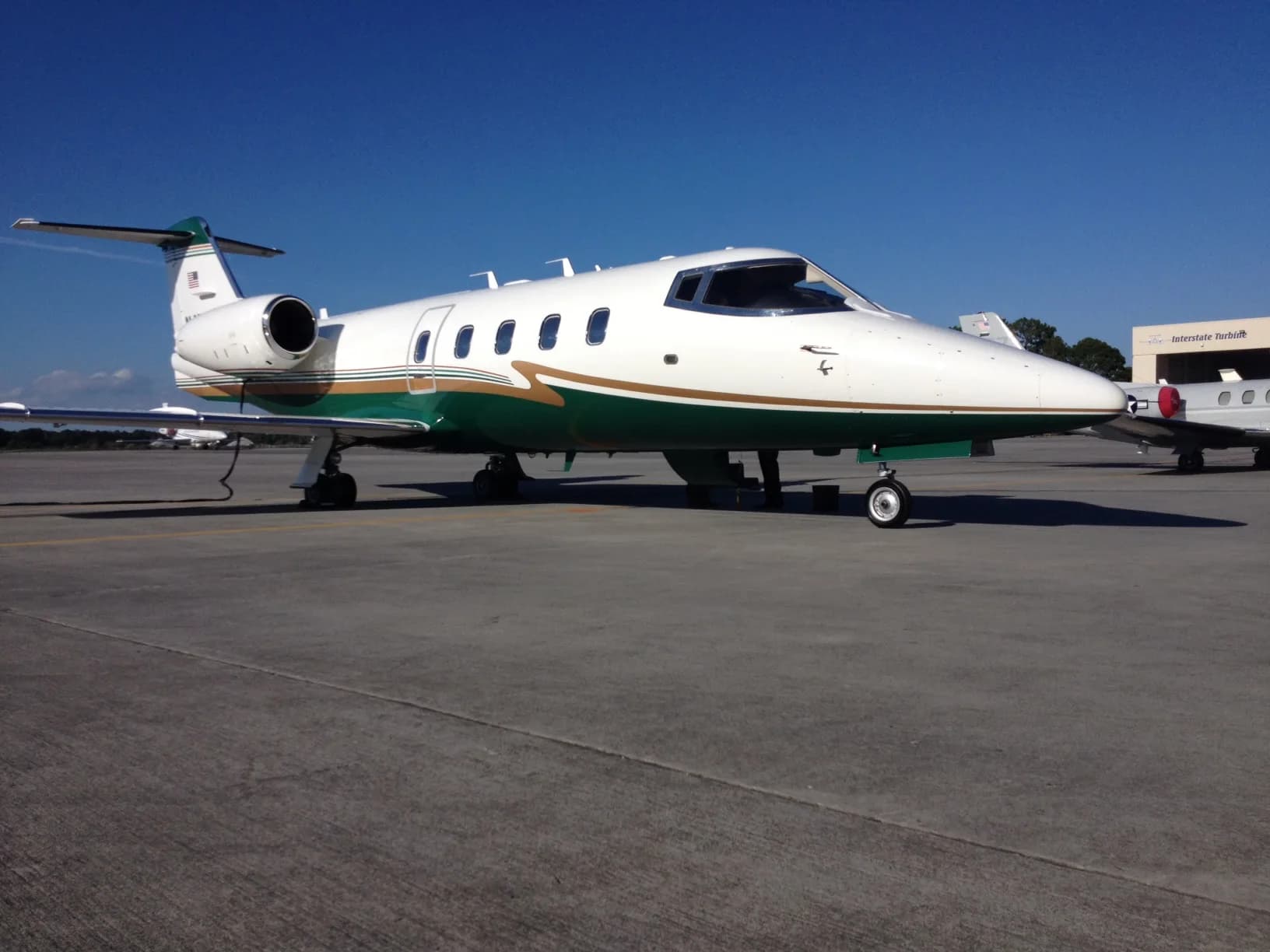 A Learjet 35A with a white and green paint scheme parked on the tarmac.