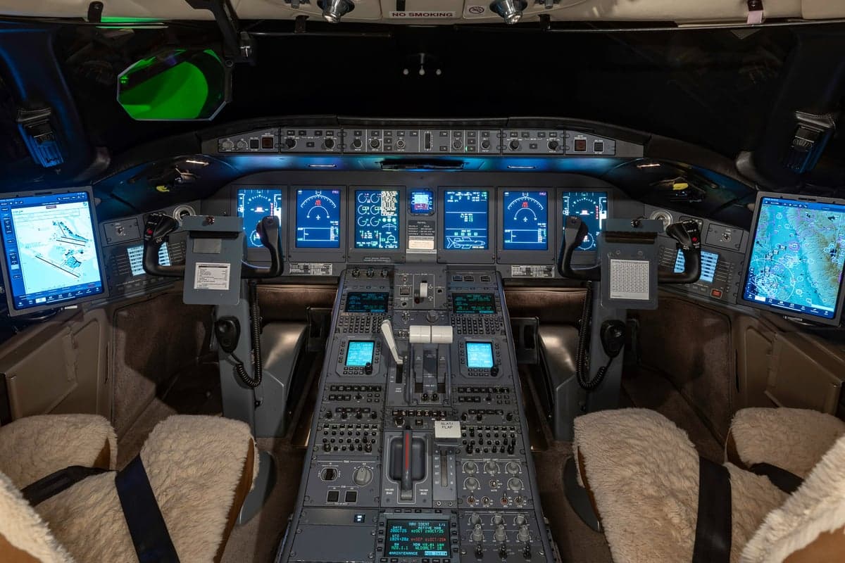 The cockpit of a Bombardier Global Express aircraft with multiple display screens.