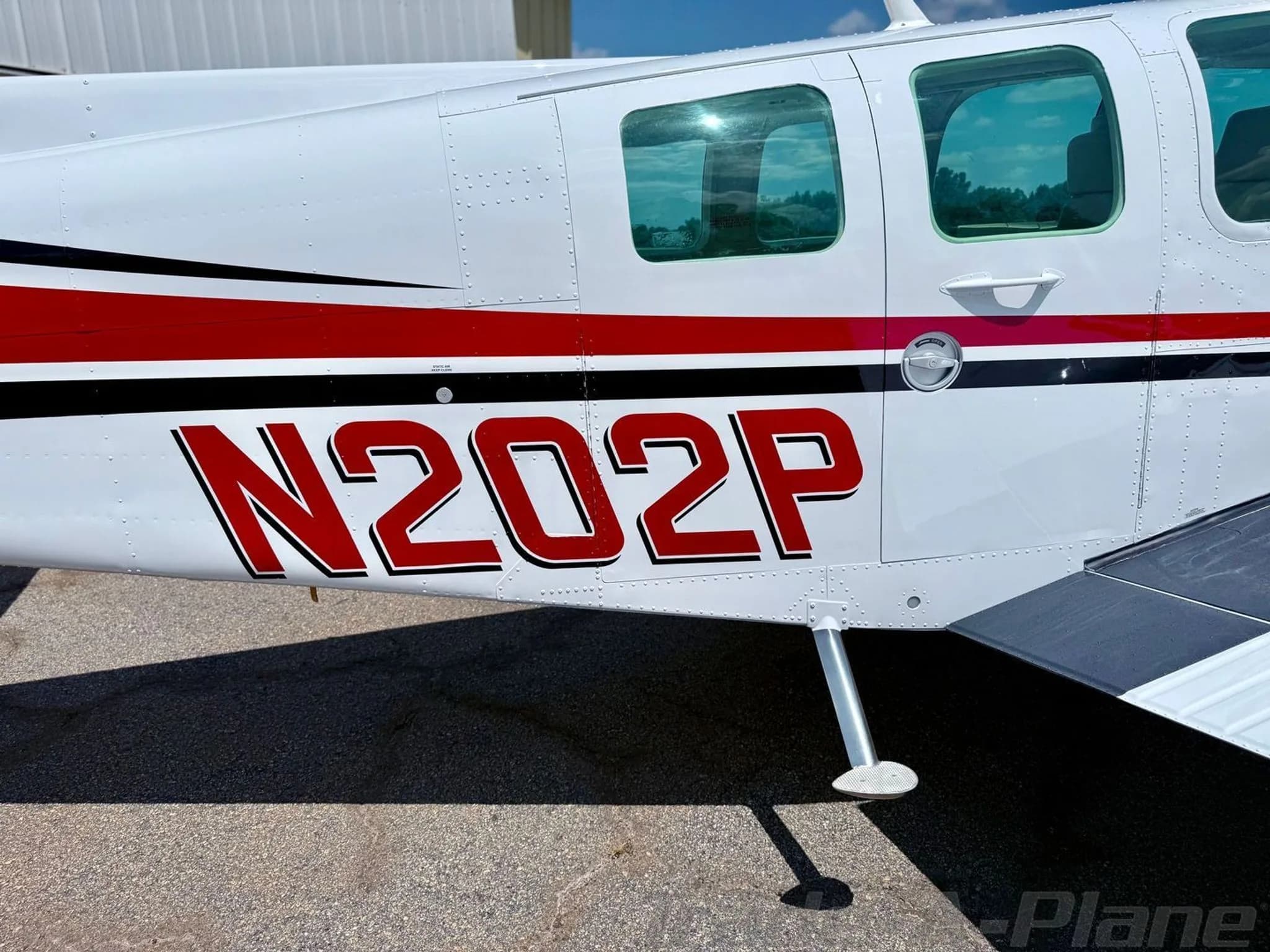 Close-up view of the white fuselage with red and black stripes and the N-number N202P.