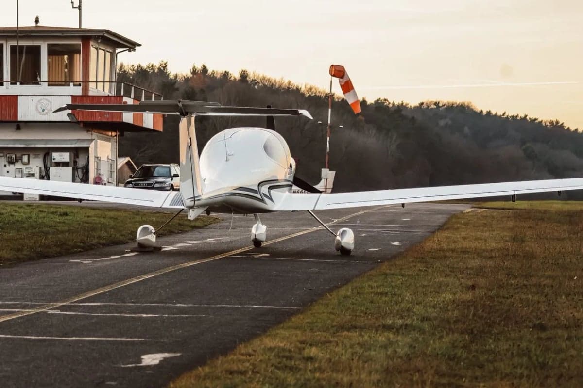 Rear view of a Diamond DA40 XLS on the runway near an airport tower.
