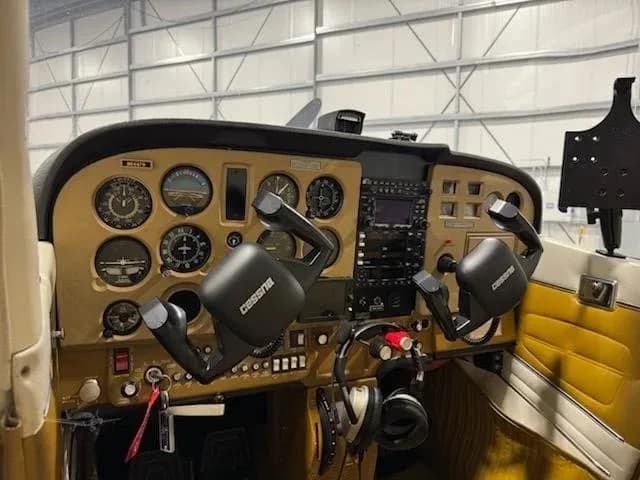 A side view of the Cessna cockpit, showing the gold instrument panel, yokes, and avionics.