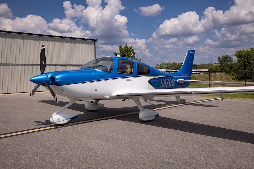 A front-side view of the blue and white Cirrus SR22 aircraft, N970S, parked on an asphalt ramp.