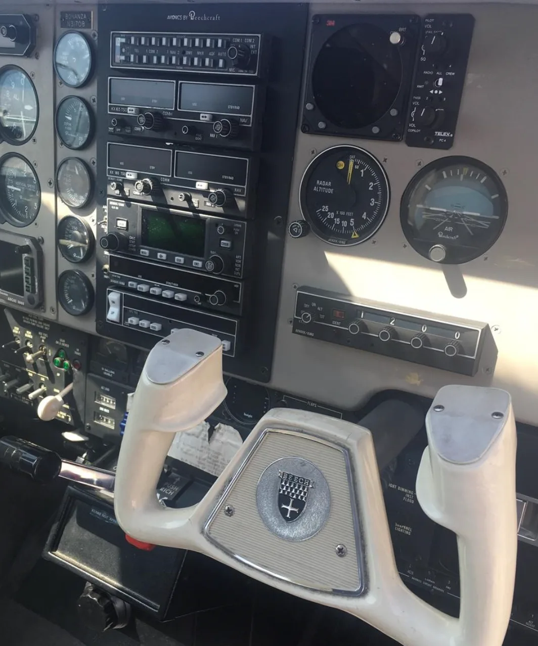 A close-up of the pilot's control yoke with the Beechcraft logo and the instrument panel in a Bonanza cockpit.