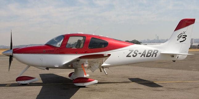 Side view of a Cirrus SR22 aircraft with a red and white paint scheme.