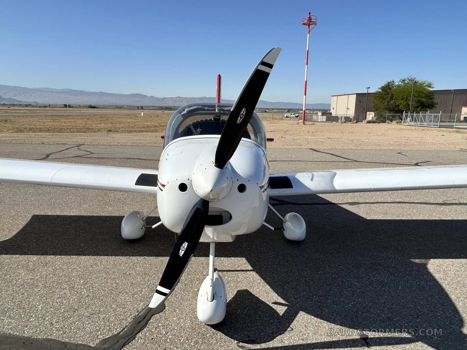 A white and red Van's RV-7 aircraft, registration N455HR, is viewed head-on from the front, showing its propeller and landing gear.